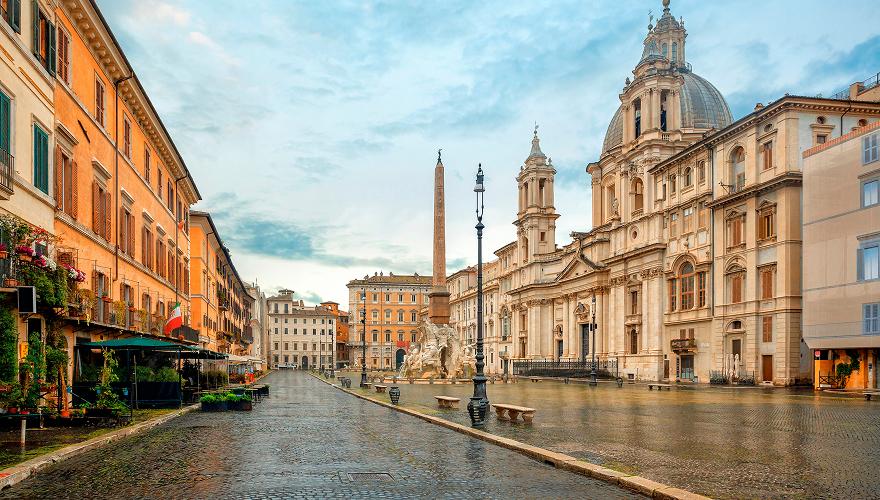 A charming European street with colorful flower shops, traditional buildings with green shutters, and a peaceful cobblestone walkway lined with potted plants and awnings